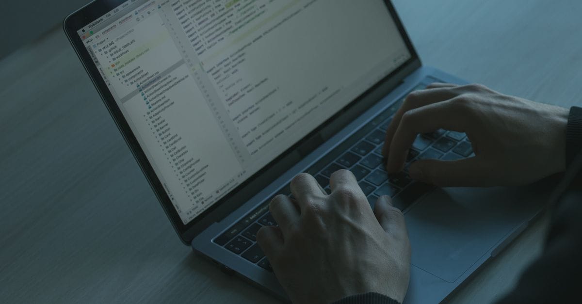 A person typing code on a laptop with a focus on cybersecurity and software development.