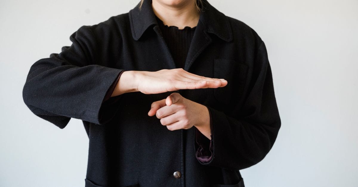 Close-up of a person demonstrating a hand gesture in a studio setting.
