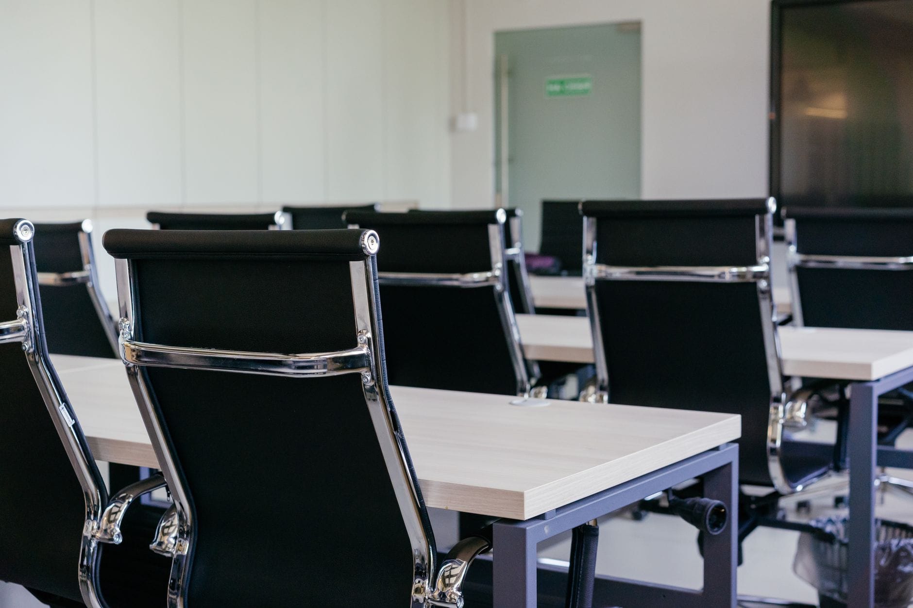 Sleek modern conference room with black chairs and white desks, suitable for business meetings.