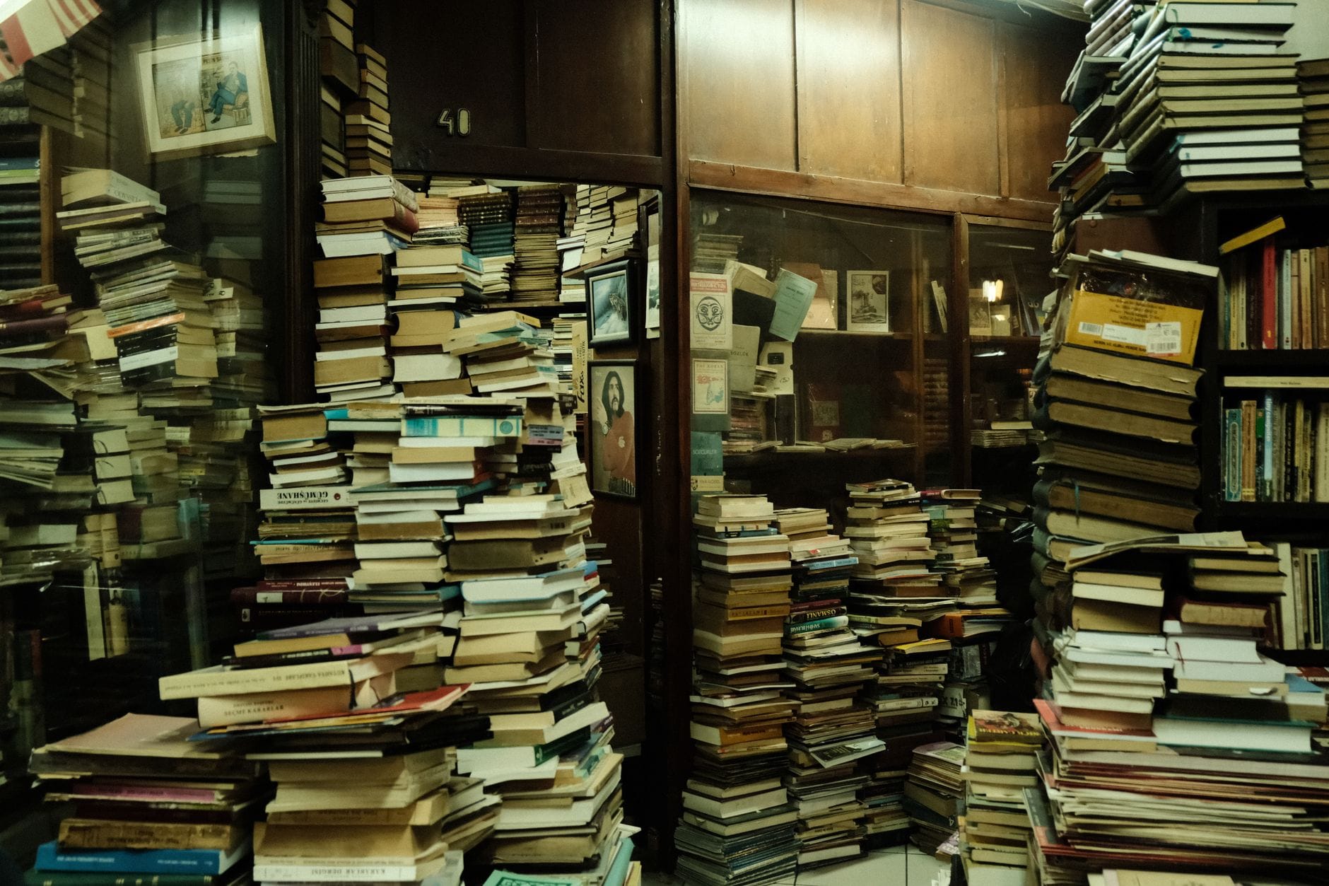A cluttered, vintage bookshop with stacks of books and a warm ambiance.