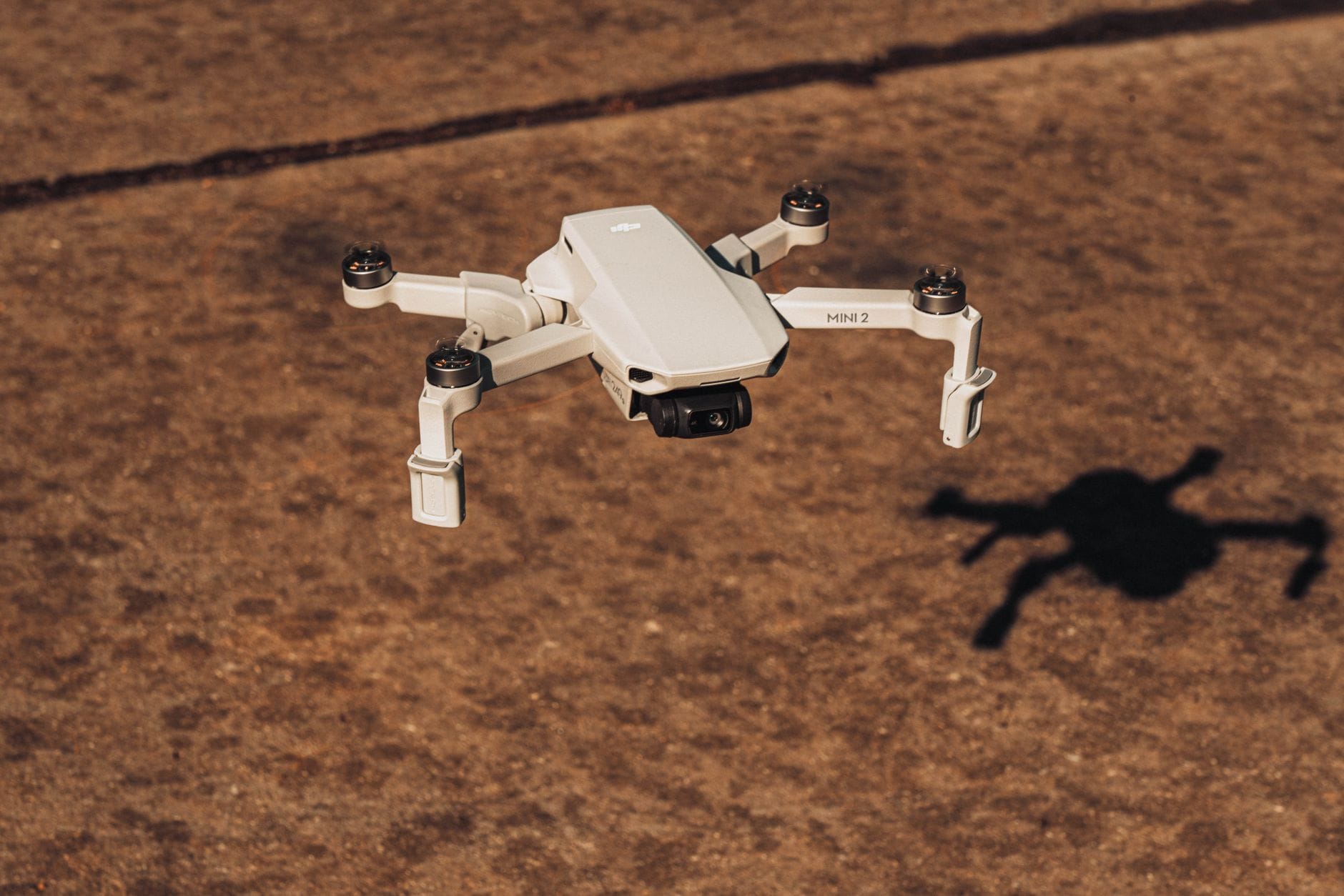 Aerial view of a modern drone in flight, casting a shadow on the ground
