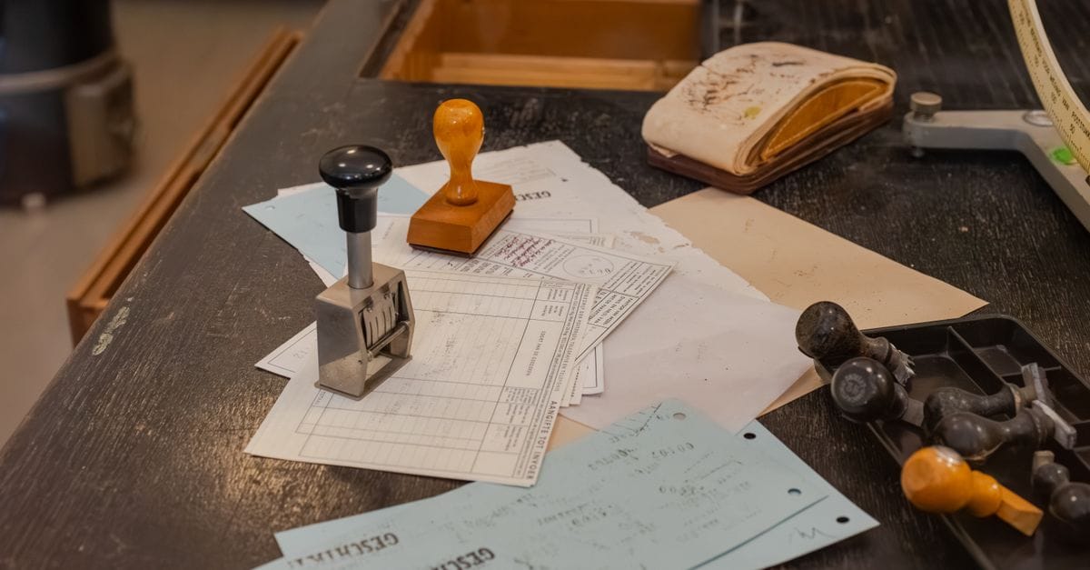 Cluttered desk with office stamps on top of various documents in an office setting.
