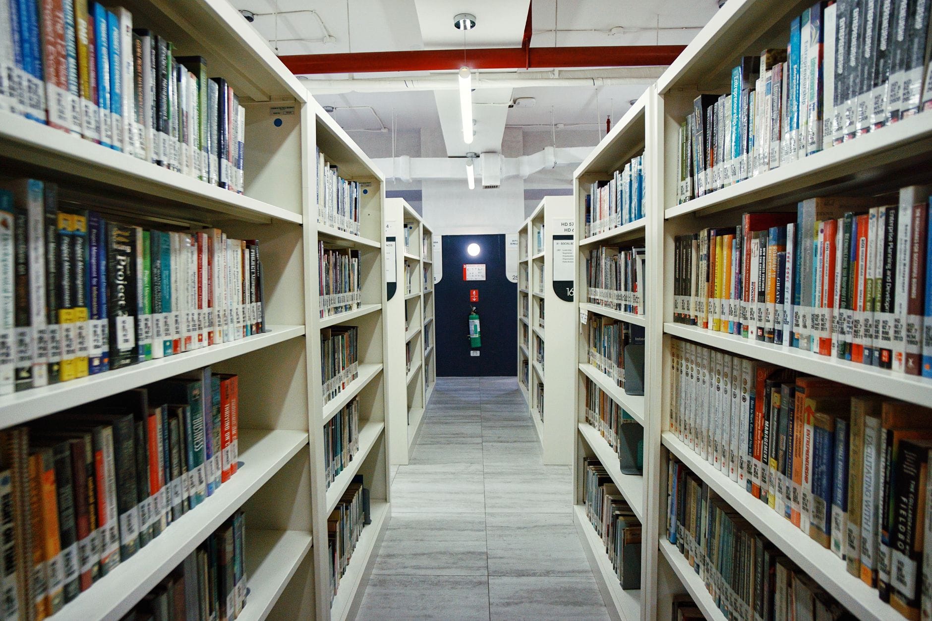 Interior view of a modern library aisle lined with bookshelves under bright lighting.