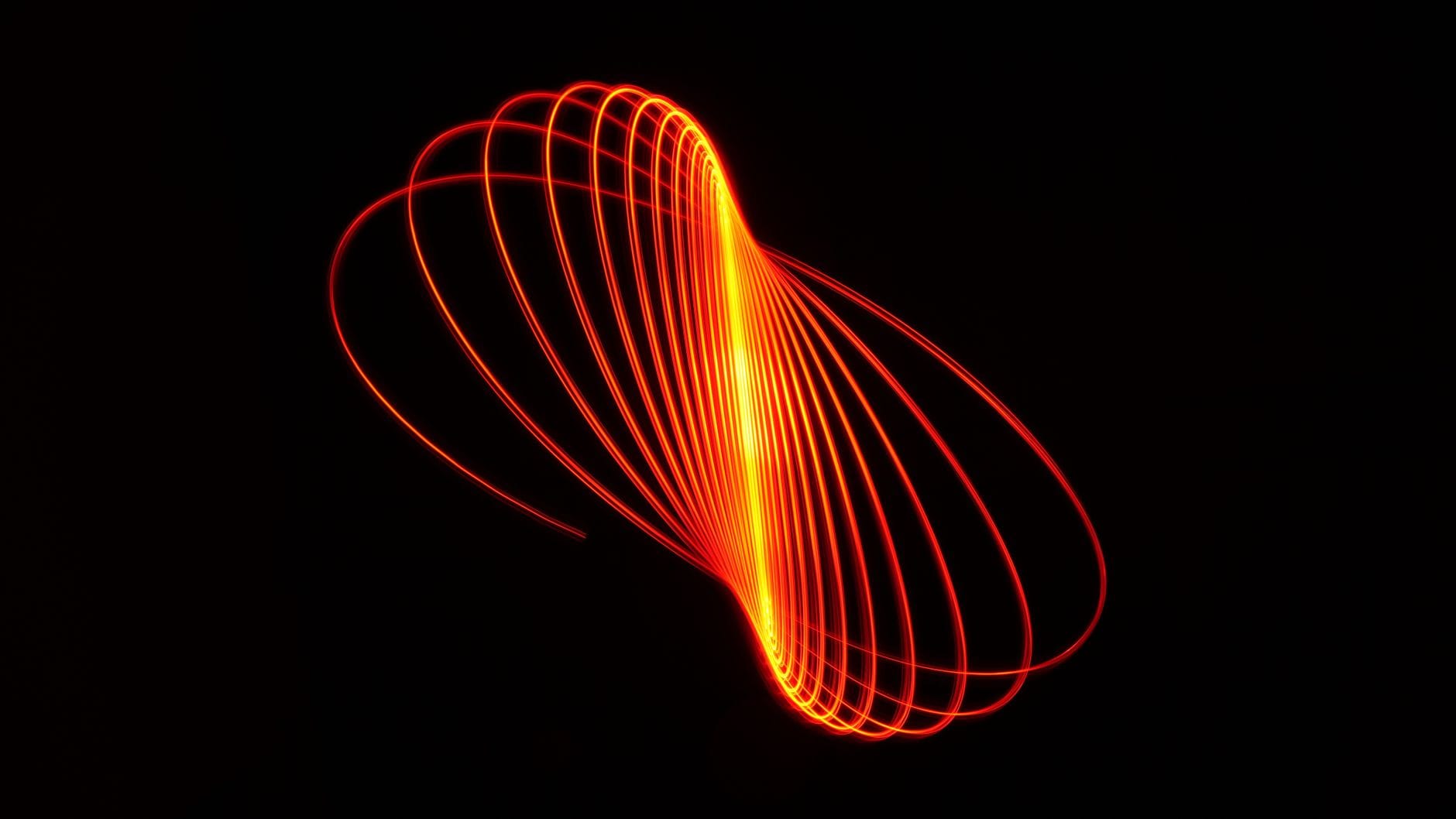 Dynamic abstract light painting featuring red glowing curves on a black background.