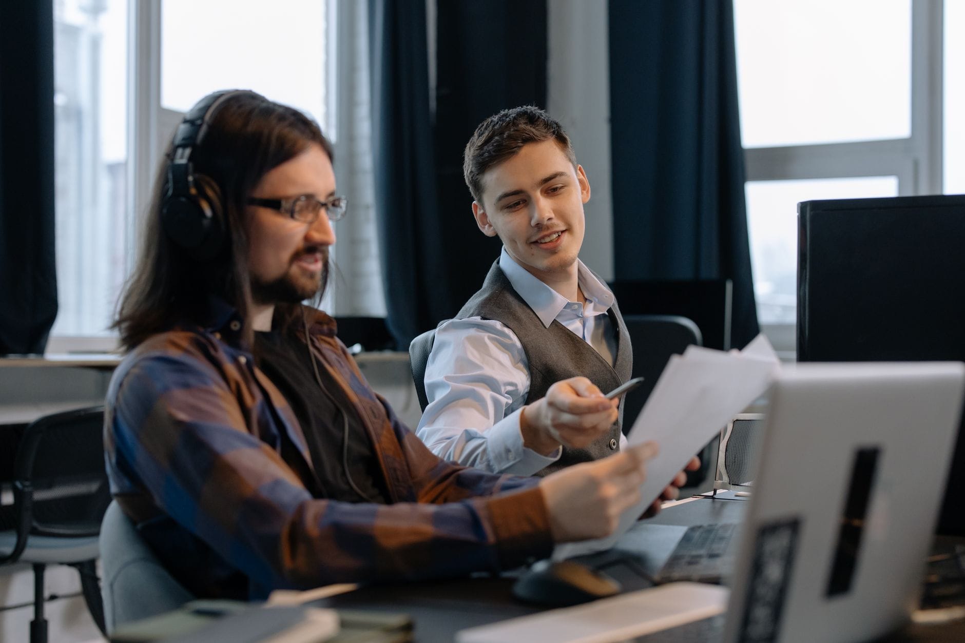 Two colleagues reviewing documents together at a modern office workstation.
