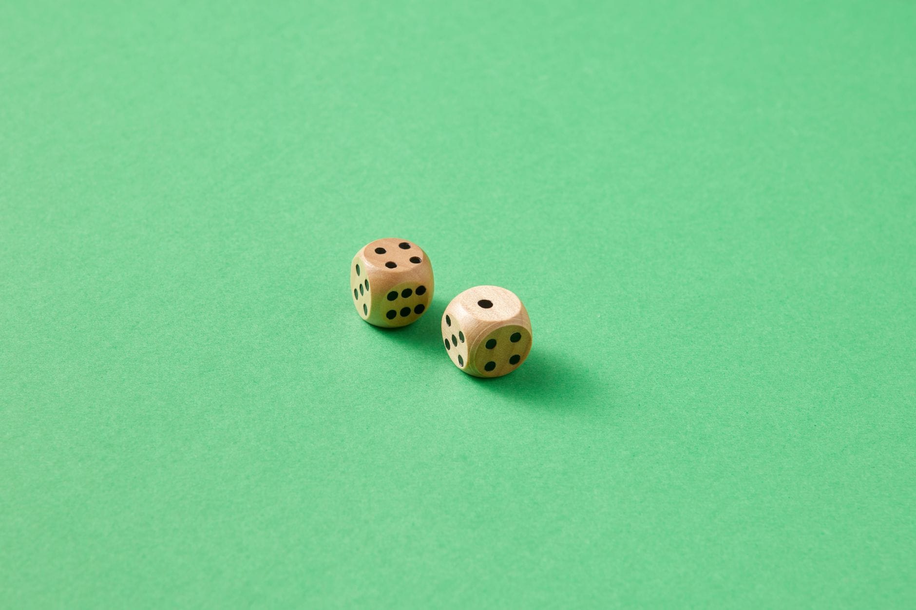 Close-up of two wooden dice on a vibrant green background.