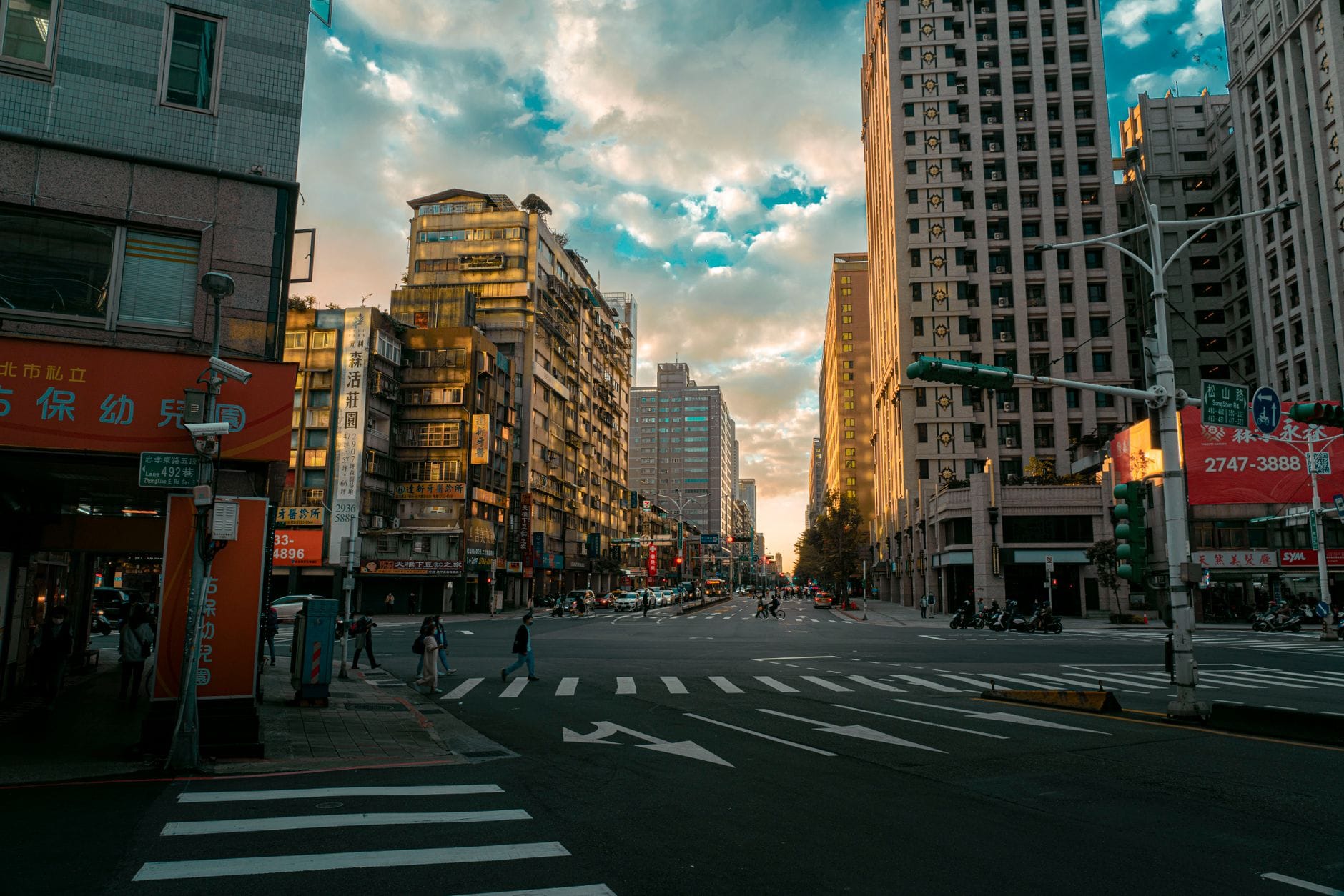 Scenic view of a vibrant city intersection at sunset with pedestrians and high-rise buildings.