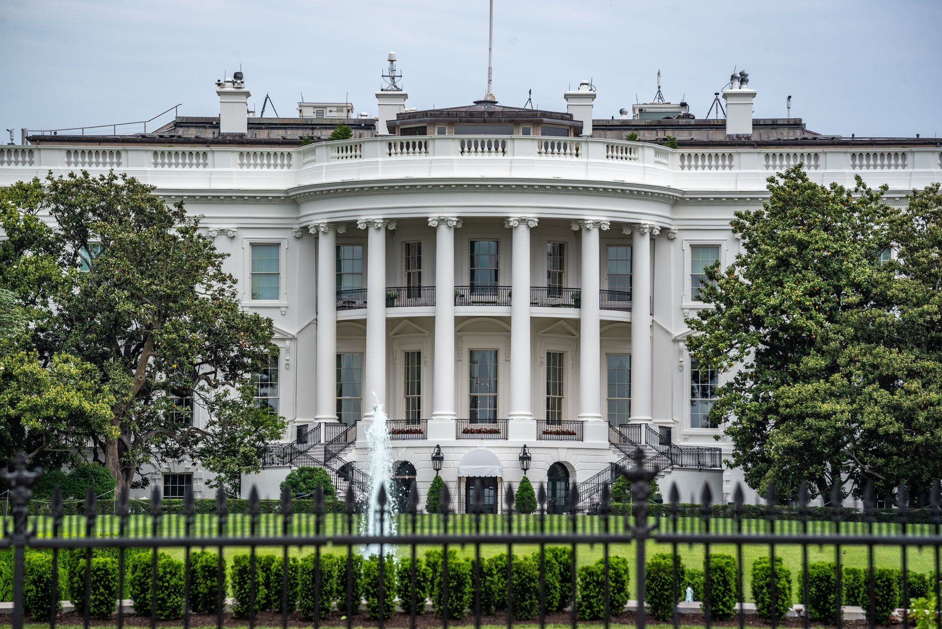 A classic view of the White House in Washington DC with lush greenery and fountains.