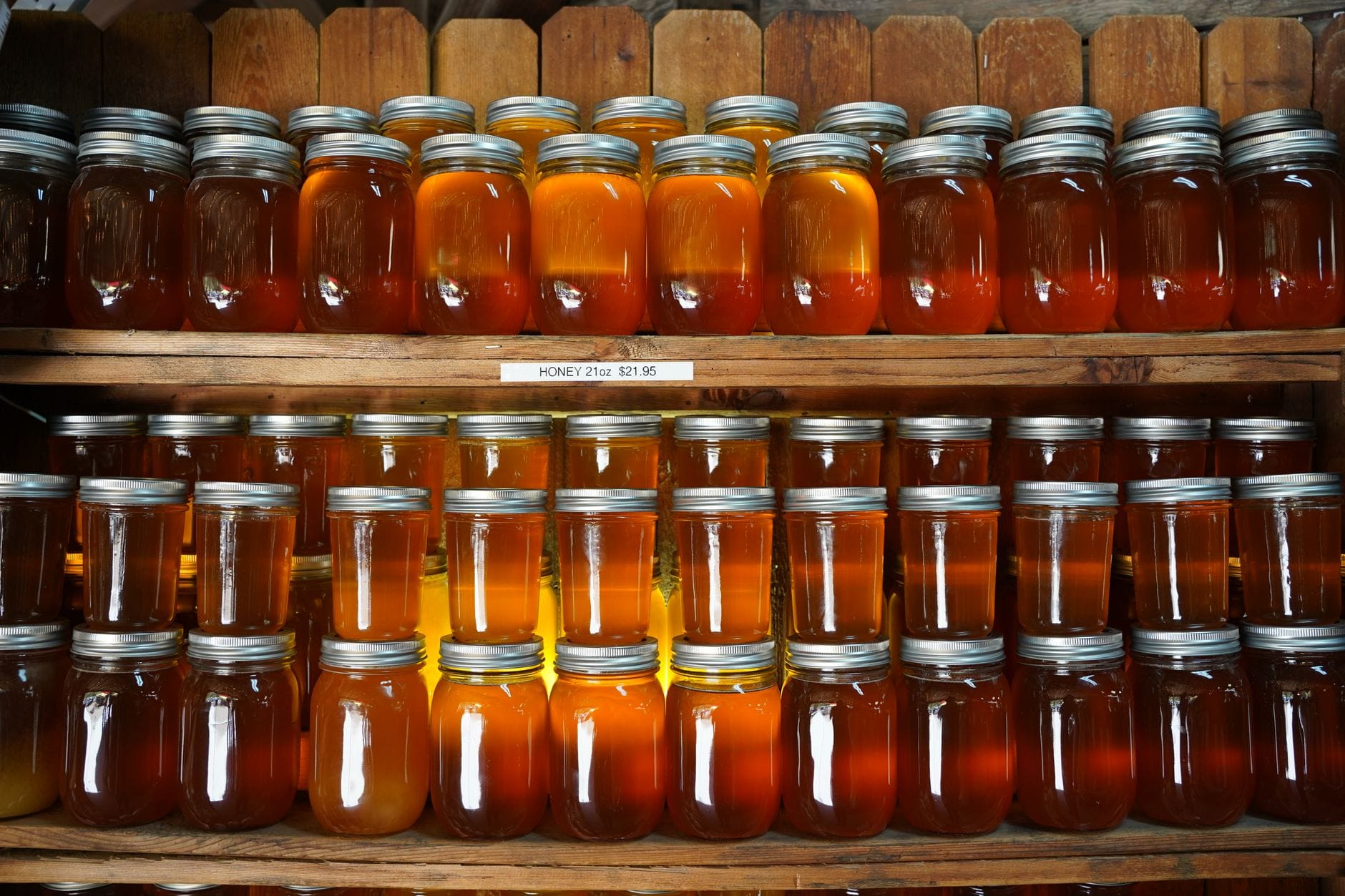 Dozens of honey jars on shelves in a rustic setting