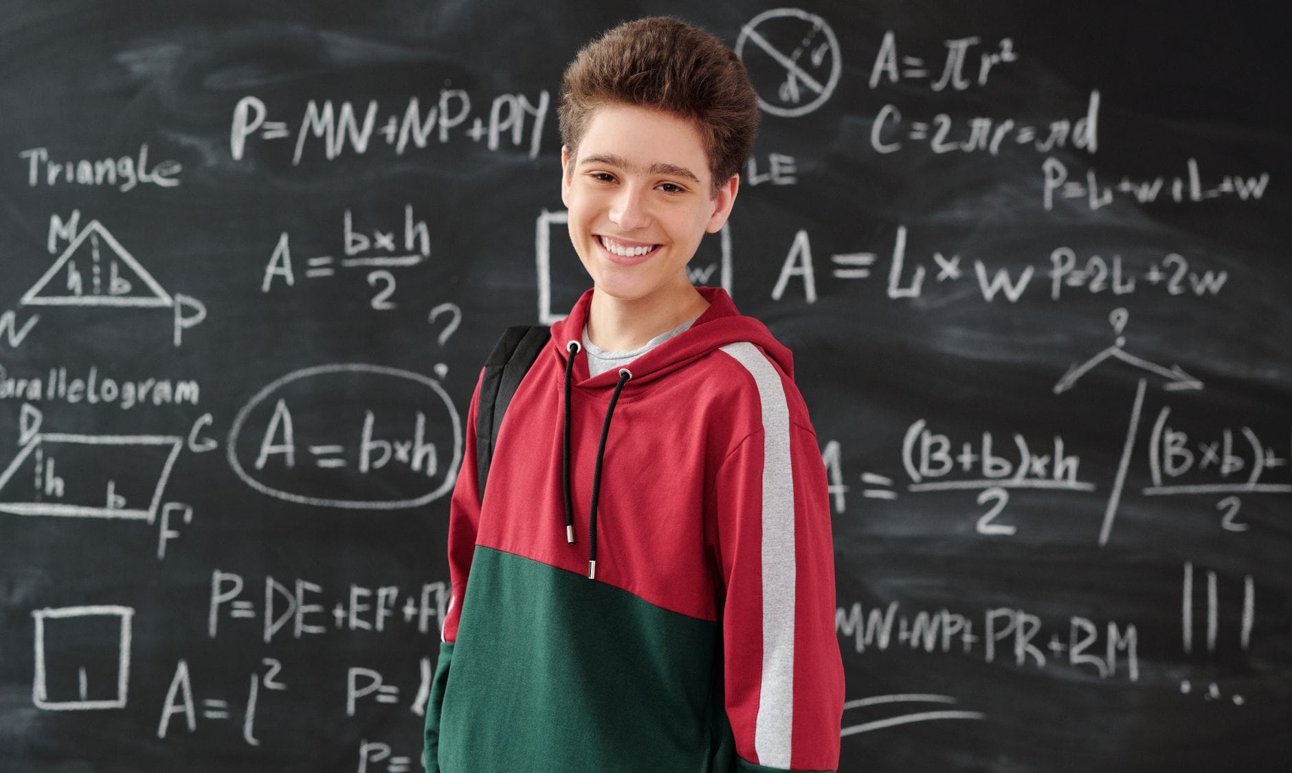 A mathematician at a chalkboard covered in equations.