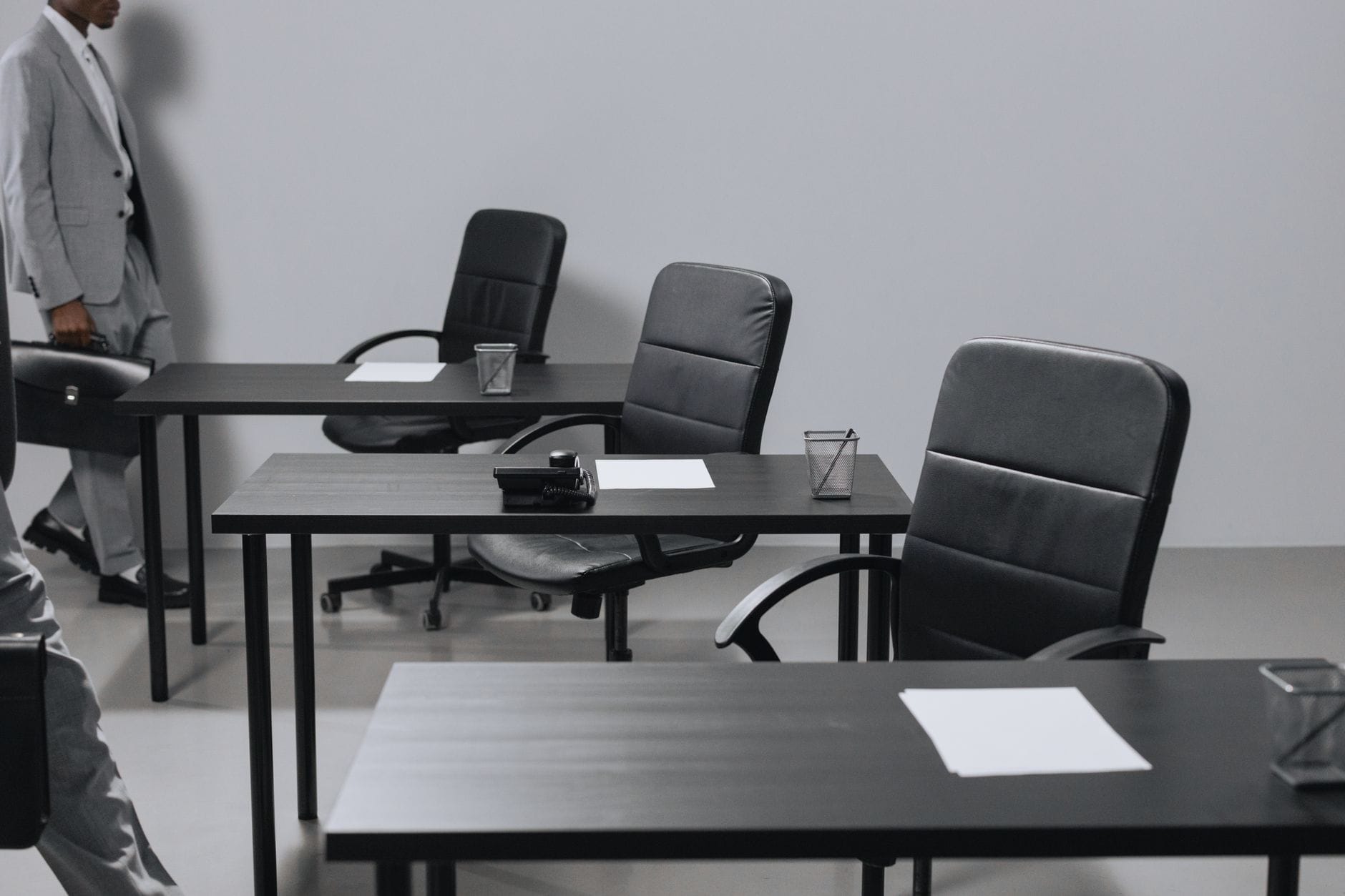 Contemporary office space with black leather chairs and desks, showcasing a minimalist design.